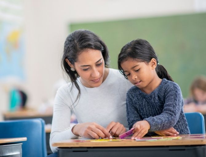 Teacher helping student with flashcards at desk