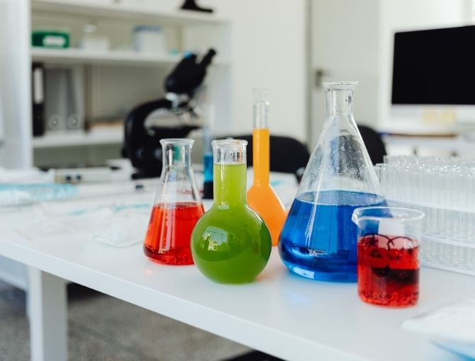 Five colorful beakers of liquid on a table