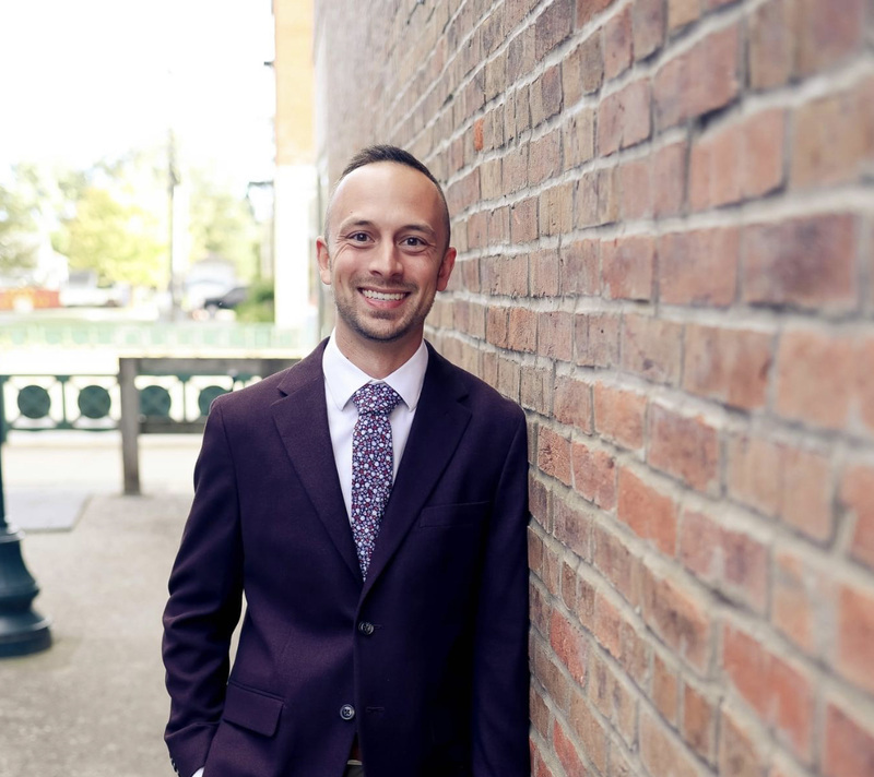 Headshot of person smiling leaning on brick wall