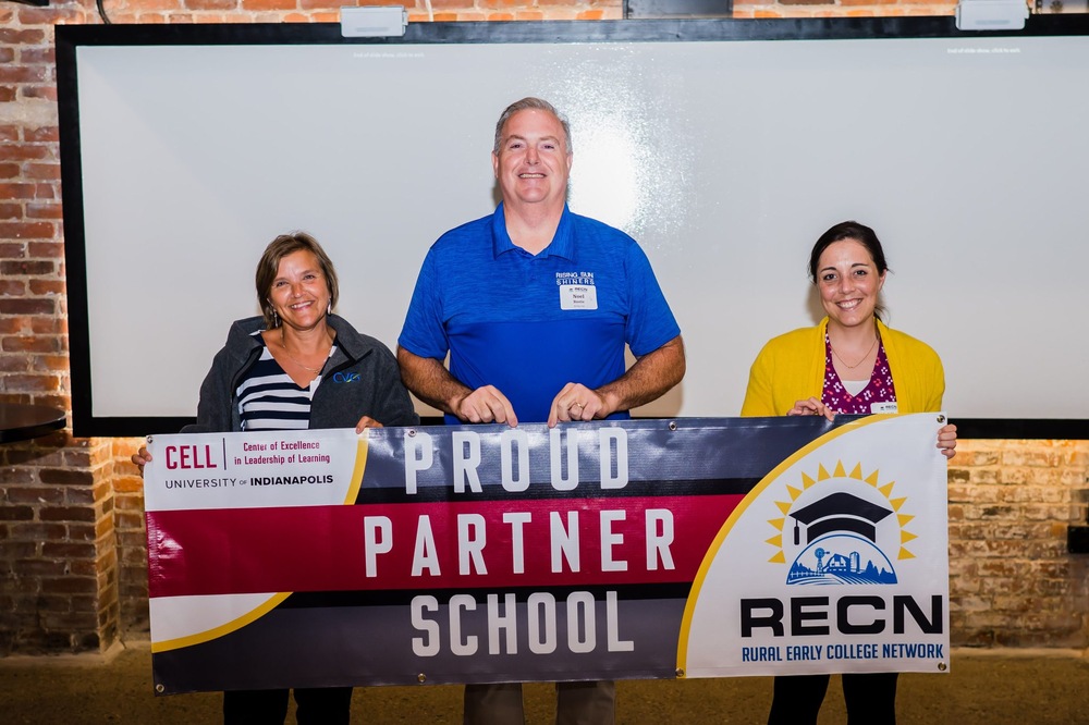 Three people holding a banner that says "Proud Partner School" with CELL and RECN logos