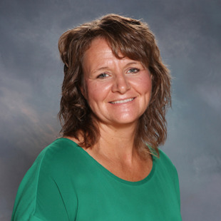 Portrait of a smiling woman with shoulder-length brown hair wearing a green top