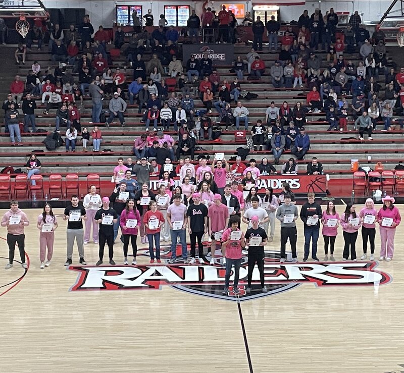 Students holding certificates on a basketball court