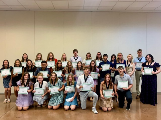 Students in three rows holding certificates
