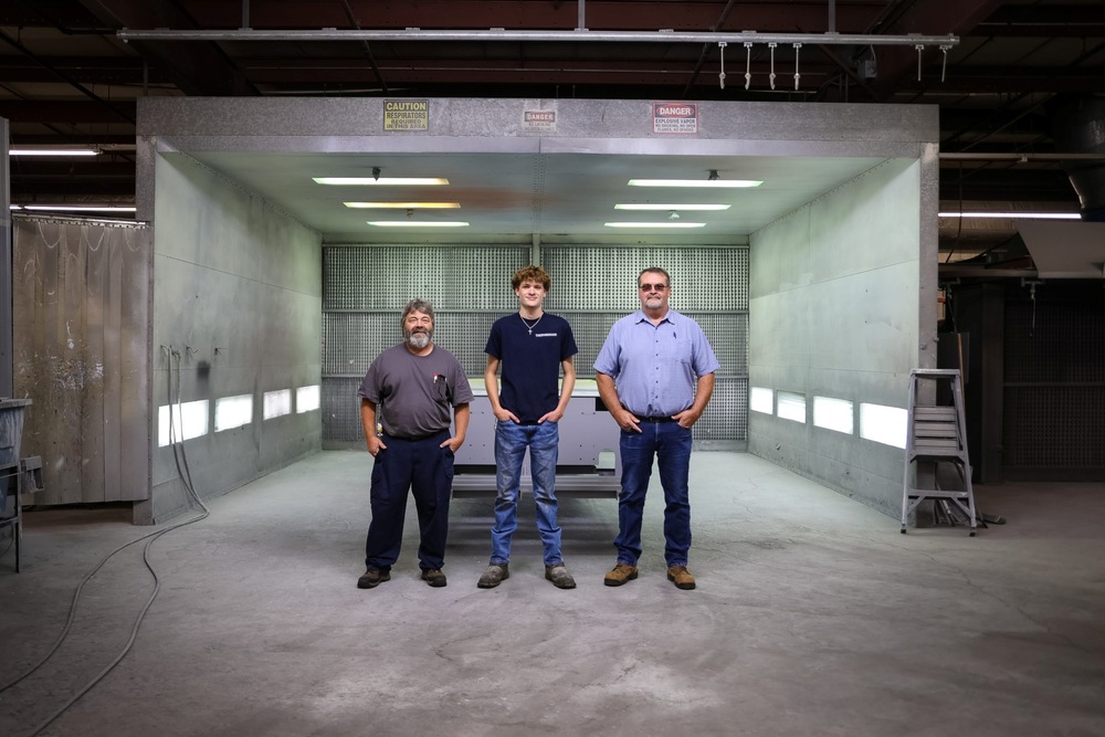 Three people standing in front of industrial area with hands in pockets
