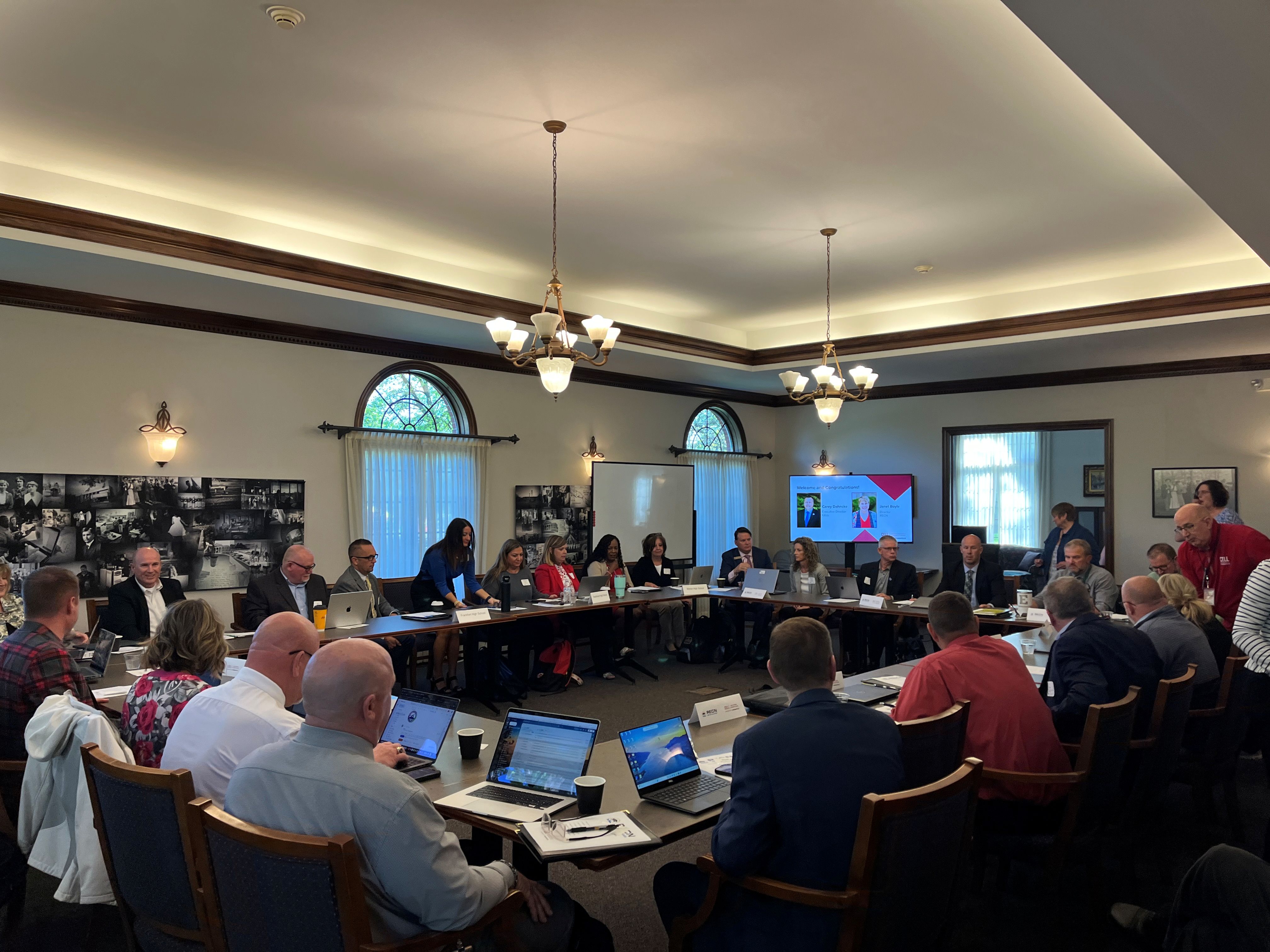 Group of educators around tables with presentation in the background