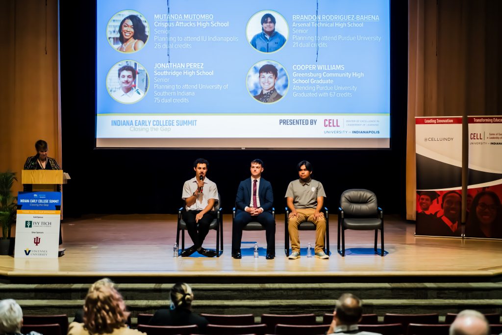Three student panelists on stage, one holding microphone
