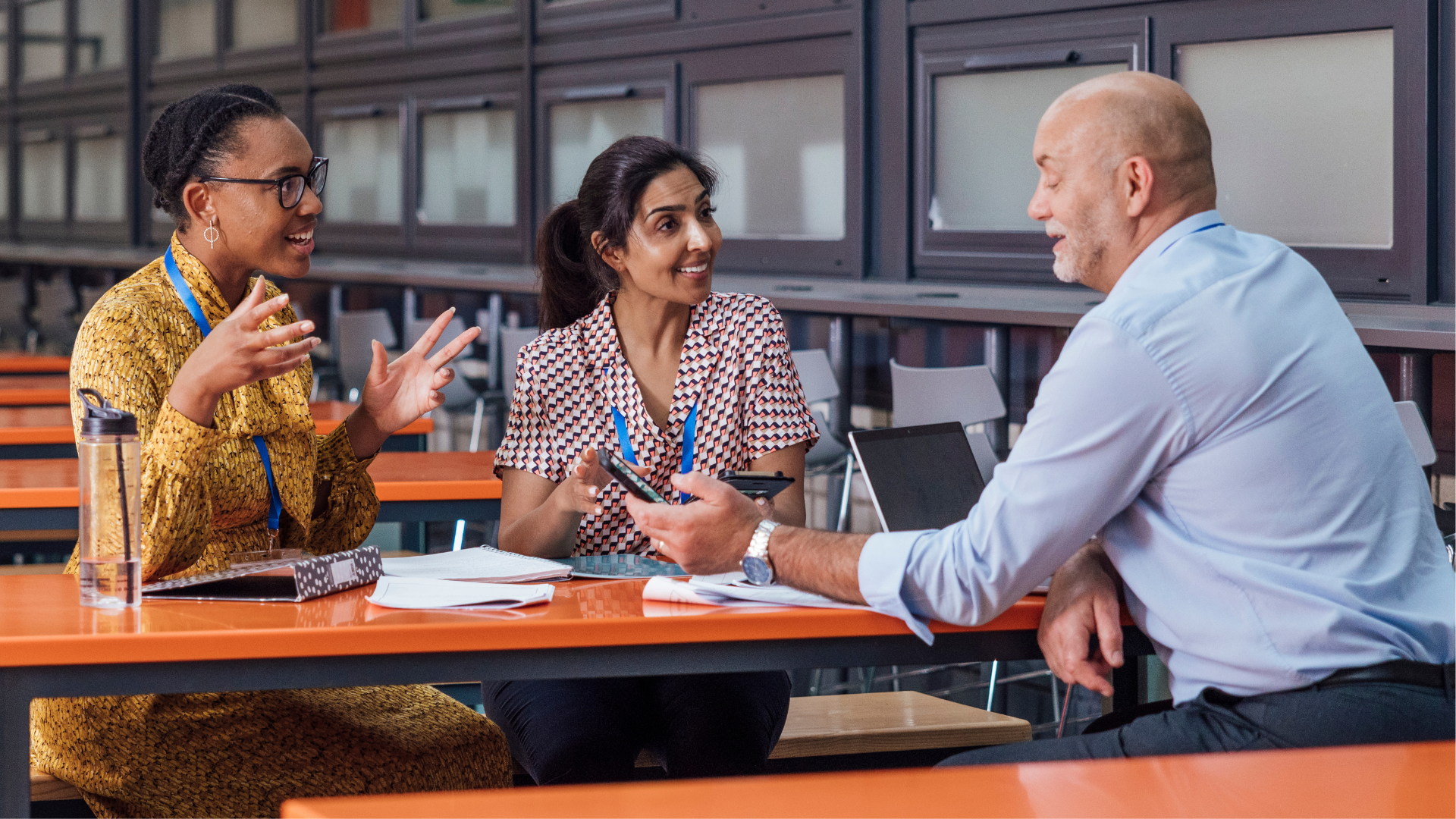 Three educators collaborating around a table in a school