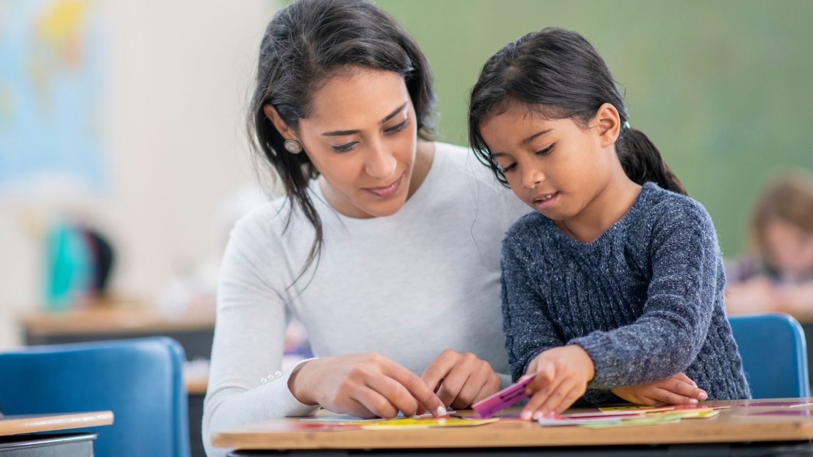 Teacher helping student with flashcards on desk