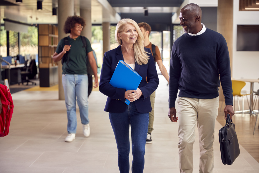 Male and female adult walking in school with students in background
