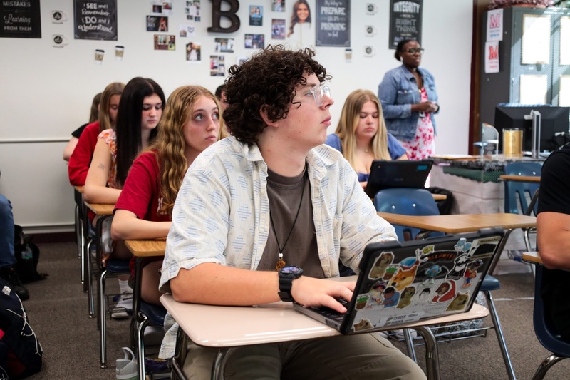 Students with laptops at desks with one in foreground
