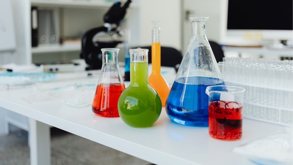 Five beakers of colorful liquid on a table